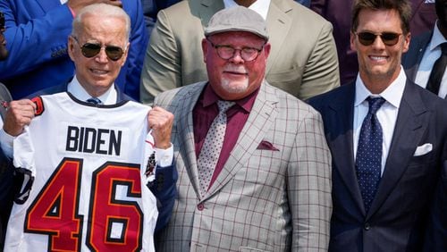 U.S. President Joe Biden holds up a Buccaneers jersey while standing next to head coach Bruce Arians and quarterback Tom Brady as he welcomes the 2021 NFL Super Bowl champions Tampa Bay Buccaneers during a ceremony on the South Lawn of the White House on July 20, 2021 in Washington, DC. (Drew Angerer/Getty Images/TNS)