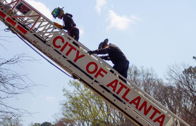 Sgt. Paul Rampley helps a Therrell High School student up an Aerial ladder during an Atlanta Fire departments Delayed Entry Program training day at the high school Thursday, March 21, 2019. STEVE SCHAEFER / SPECIAL TO THE AJC