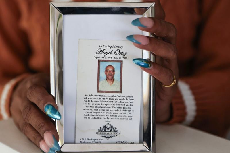 Sandra Outler holds a photo of her father, Angel Manuel Ortiz, who was killed at Calhoun State Prison in 2019. The 60-year-old Ortiz was days away from being paroled when he was placed in a holding cell with Frank Hardy. According to a civil suit filed by Ortiz’s family, Hardy had threatened to kill anyone placed in a cell with him. (Natrice Miller/Natrice.miller@ajc.com)