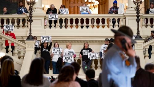 Protesters for better treatment of inmates hold signs during an unrelated press conference at the state Capitol in Atlanta on Wednesday. (Ben Gray / Ben@BenGray.com)