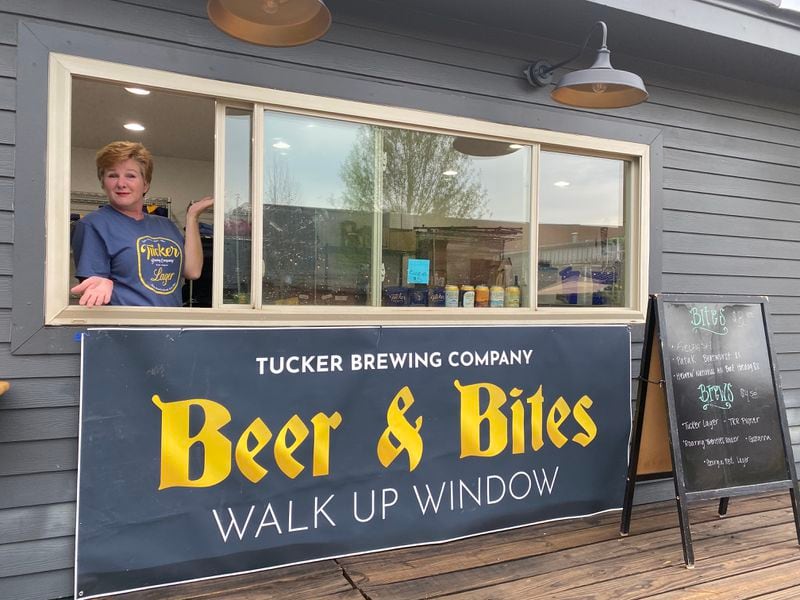 A Tucker Brewing employee manages the walk-up window in the beer garden, where patrons can purchase items not on the regular food menu, including kielbasa, bratwurst and all-beef hot dogs. Ligaya Figueras/ligaya.figueras@ajc.com