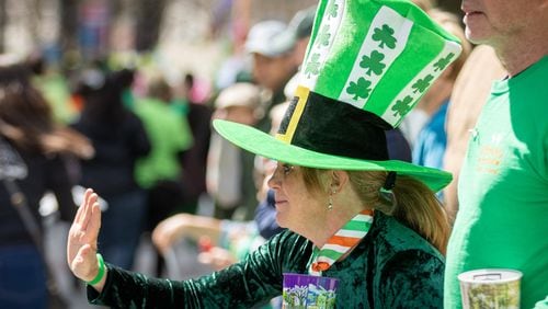 Kathy Workman waves as the Atlanta St. Patrick's Parade heads down Peachtree Street on March 11, 2023. (Steve Schaefer/steve.schaefer@ajc.com)