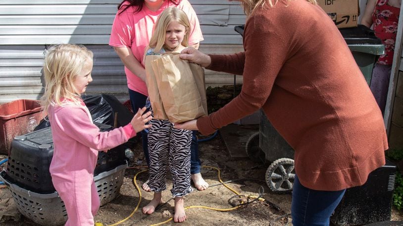 Marianne Glaser delivers lunches to Paisley Hugenschmidt as her mother, Katherine Hugenschmidt, and her sister Samantha look on Wednesday, March 25, 2020. STEVE SCHAEFER / SPECIAL TO THE AJC