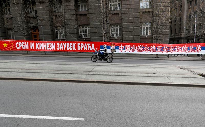FILE - A motorcyclist rides past a billboard showing Serbian and Chinese flags that read: "Serbs and Chinese brothers forever" placed on a street prior to a curfew set up to help prevent the spread of the new coronavirus in Belgrade, Serbia, Monday, April 13, 2020. Chinese President Xi Jinping will visit France, Serbia and Hungary next week as Beijing appears to seek a larger role in the conflict between Russia and Ukraine that has upended global political and economic security. (AP Photo/Darko Vojinovic, File)