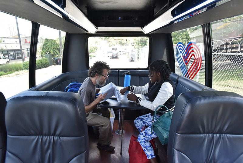 Mathew Reed, left, Mercy Care case manager, helps client Candace Mathews with online application for Supplemental Security Income (SSI) inside Mercy Care van at a homeless encampment near Georgia Tech campus. (Hyosub Shin / Hyosub.Shin@ajc.com)