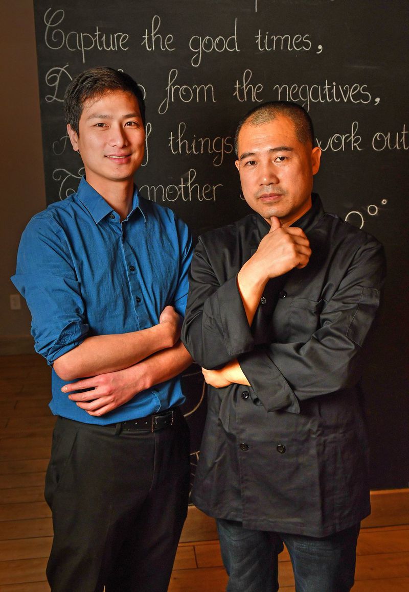 Sho You (left) and executive chef Xue Guo Wu, co-owners of Urban Wu, are shown in front of inspirational words written on the wall of their Buckhead restaurant. They offer recipes for celebrating the Lunar New Year. CONTRIBUTED BY CHRIS HUNT PHOTOGRAPHY