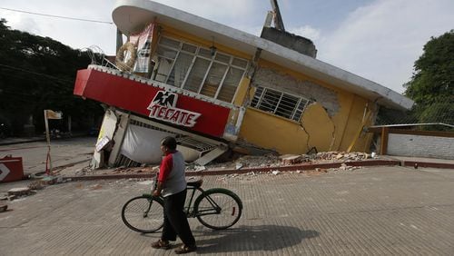 A man walks his bike past a building felled by a 7.1 earthquake, in Jojutla, Morelos state, Mexico, Wednesday, Sept. 20, 2017. Police, firefighters and ordinary Mexicans are digging frantically through the rubble of collapsed schools, homes and apartment buildings, looking for survivors of Mexico’s deadliest earthquake in decades as the number of confirmed fatalities climbs. (AP Photo/Eduardo Verdugo)