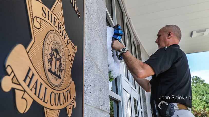 Hall County Sheriff's Deputy T. Ambercrombie hangs wreaths in front of the sheriff's office on Monday. A deputy died after a Sunday night shootout with suspects believed to be linked to recent break-ins and robberies. AJC photo: John Spink