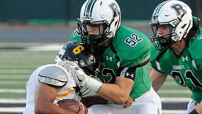 Roswell LB Mitch Stone (52) tackles Central Gwinnett QB Hunter Sims with backup from LB Sam Diroberto (31) during Friday's game.