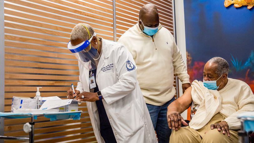 Morehouse School of Medicine nurse Dawn-Marie Aime (left) gathers information for records before administering the first of two Moderna COVID-19 vaccines to baseball legend Henry Aaron (seated) and other people prominent in civil rights on January 5, 2021. (Jenni Girtman for The Atlanta Journal-Constitution)