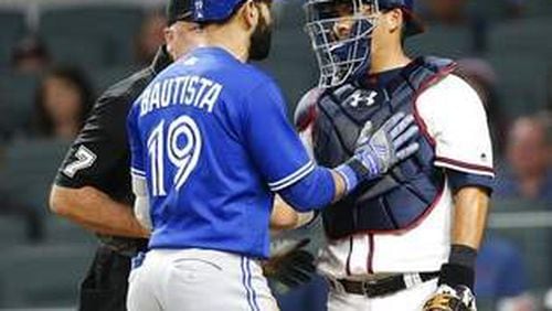 Toronto’s Jose Bautista and Braves catcher Kurt Suzuki exchange words after Bautista’s bat-flip and stare-down of Braves following an eighth-inning home run. (AP photo)