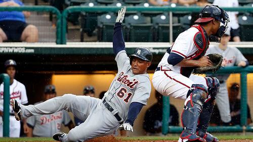 Ezequiel Carrera slides past Braves catcher Christian Bethancourt with the winning run in the ninth inning of a 2014 spring training game when Carrera was with the Tigers. The Braves signed him to a minor-league deal this week.