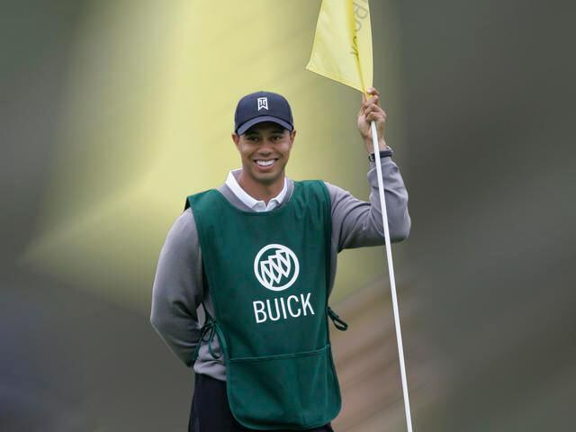 Tiger Woods holds the flag for golfer John Abel, who won a contest to have Tiger Woods caddie for him, at South Course at Torrey Pines, San Diego, California in October 2008.