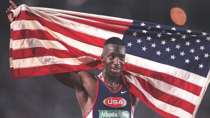 American Michael Johnson exalts in the glory of winning the gold medal by carrying the American flag around the stadium after winning the 400 m run in an Olympic record time Monday, July 29, 1996, at the Olympic Stadium in Atlanta. (Jonathan Newton/AJC)