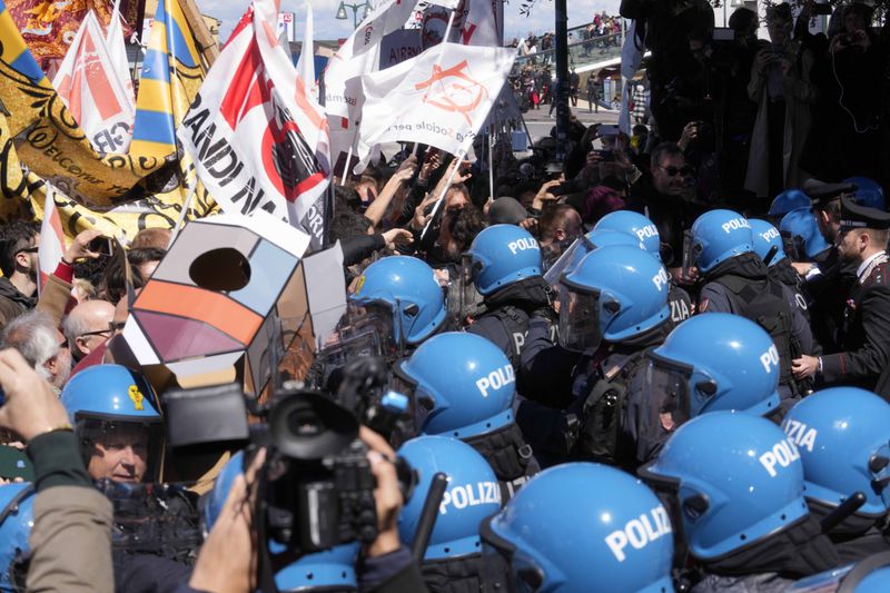 Citizens and activists confront police during a demonstration against Venice Tax Fee in Venice, Italy, Thursday, April 25, 2024. The fragile lagoon city of Venice begins a pilot program Thursday to charge daytrippers a 5 euro entry fee that authorities hope will discourage tourists from arriving on peak days. The daytripper tax is being tested on 29 days through July, mostly weekends and holidays starting with Italy's Liberation Day holiday Thursday. Officials expect some 10,000 people will pay the fee to access the city on the first day, downloading a QR code to prove their payment, while another 70,000 will receive exceptions, for example, because they work in Venice or live in the Veneto region. (AP Photo/Luca Bruno)