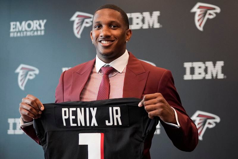Atlanta Falcons first round draft choice quarterback Michael Penix Jr., holds a Falcons jersey during a news conference Friday, April 26, 2024, in Flowery Branch, Ga. (AP Photo/John Bazemore)