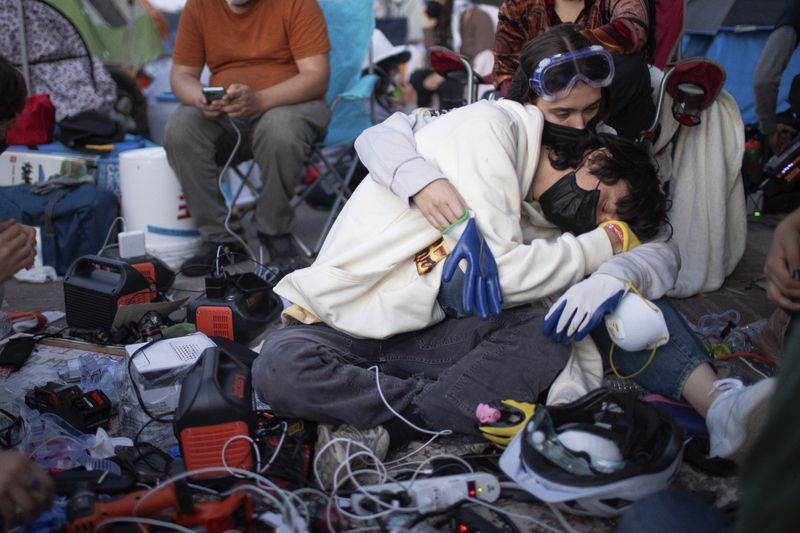 FILE - Pro-Palestinian demonstrators embrace while charging devices at an encampment on the UCLA campus Wednesday, May 1, 2024, in Los Angeles. (AP Photo/Ethan Swope, File)