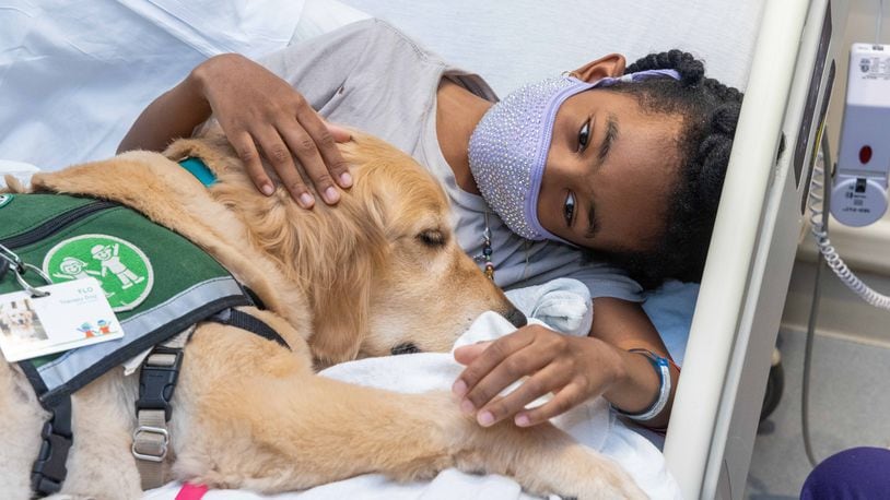 Amiaya Brown, 9, snuggles with therapy dog, Flo, in her hospital room at Children's Healthcare of Atlanta Egleston in Decatur. The Canines for Kids program at Children's Healthcare of Atlanta began with one dog, Casper, in 2009 and now has 14 dogs on staff. The dogs visit with the pediatric patients to make their time in the hospital easier.
 SKINNER FOR THE ATLANTA JOURNAL-CONSTITUTION