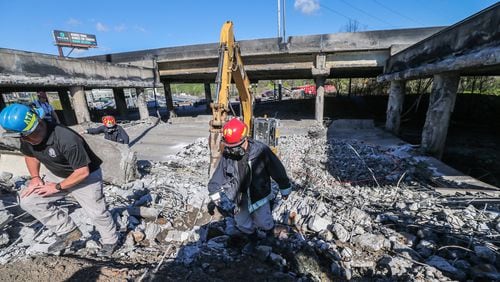Officials look over the rubble from the I-85 collapse Friday in Buckhead. The highway in Atlanta is closed in both directions after a massive fire during the Thursday evening rush hour collapsed a portion of the northbound lanes near Piedmont Avenue.