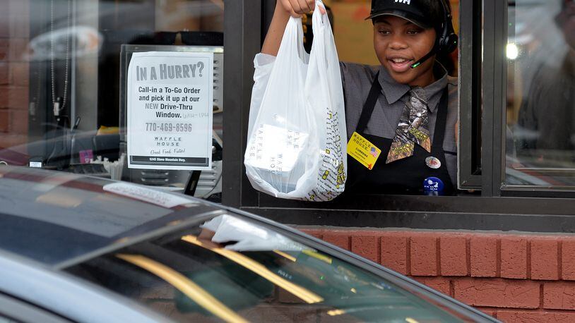 Currena Curry hands a customer their food at the Waffle House drive-thru window in Stone Mountain. It’s the only Waffle House in the 1,800-restaurant chain to have a drive thru. BRANT SANDERLIN/BSANDERLIN@AJC.COM
