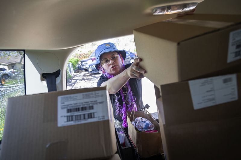 Kimra Luna fills the back of their car with boxes of materials which will be used to make reproductive health kits which are then offered free to local business in Boise, Idaho, on Friday, April 12, 2024. Luna, a doula and reproductive care activist, lives in a state with some of the strictest abortion laws in the nation. (AP Photo/Kyle Green)