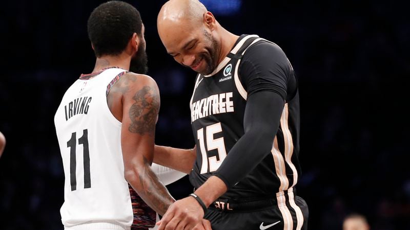 Hawks guard Vince Carter (15) greets Nets guard Kyrie Irving (11) as he comes into the game during the first quarter Sunday, Jan. 12, 2020, in New York. It was Carter's last game in New York and Irving's first game since going out with a shoulder injury two months ago.