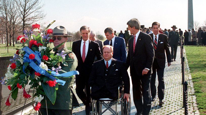 In this file photo, then-U.S. Sen. Max Cleland, D-Ga. (in wheelchair), and fellow senators — (left to right) Bob Kerrey, D-Neb.; John McCain, R-Ariz.; Charles Hagel, R-Neb.; John Kerry, D-Mass.; and Chuck Robb, D-Va. — walk along the Vietnam Veterans Memorial wall behind the wreath they would lay to commemorate the 15th anniversary of groundbreaking for the memorial. All six senators served in Vietnam, and Cleland lost both legs and an arm in that war. He was awarded the Silver Star, the Bronze Star, and the Soldier’s Medal. He appears briefly in the introduction of the documentary series. (Photo by Rick McKay/Washington Bureau)