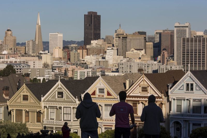 The silhouettes of pedestrians stand in front of Victorian homes and the downtown skyline in San Francisco, where the median home price is more than twice that of Atlanta. (David Paul Morris/Bloomberg)
