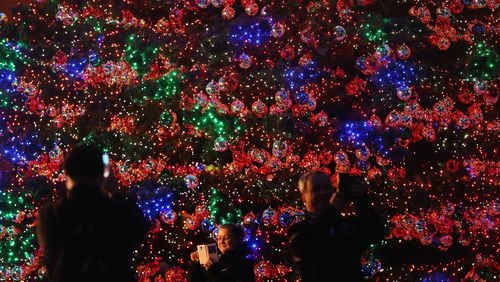 FILE PHOTO: People snap photos in front of a giant, illuminated Christmas tree.