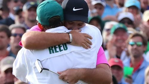 Patrick Reed hugs his caddy Kessler Karain after making a par putt on the 18th green to win the Masters Tournament Sunday, April 8, 2018, at 15-under par at Augusta National Golf Club.