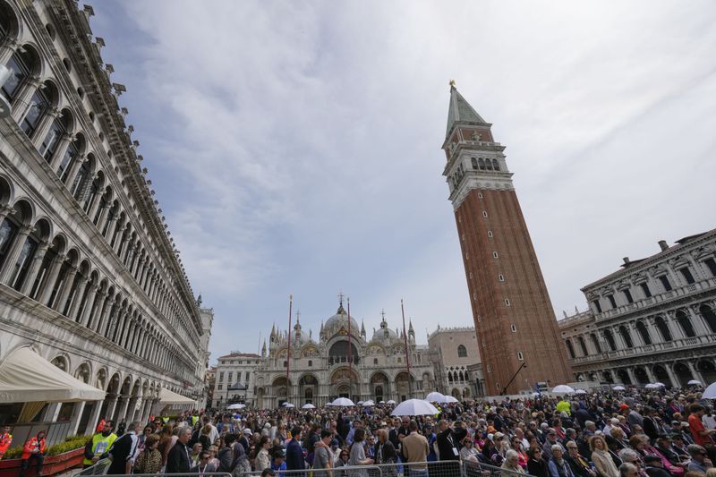 Faithful gather in St. Mark's Square, during a mass celebrated by Pope Francis in Venice, Italy, Sunday, April 28, 2024. The Pontiff arrived for his first-ever visit to the lagoon town including the Vatican pavilion at the 60th Biennal of Arts. (AP Photo/Antonio Calanni)