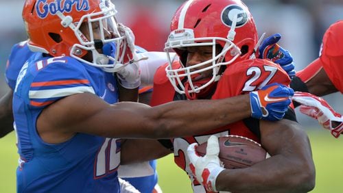 UGA running back Nick Chubb is brought down Gators DB Quincy Wilson during the 2014 Georgia-Florida game. Georgia was ranked in the top 10 and a 12-point favorite against the Gators, but lost 38-20. (Brant Sanderlin/AJC file photo)