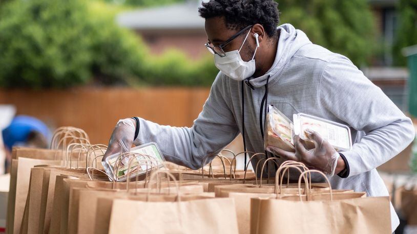 Erik Roberson with CHRIS 180 stuffs bags with food to be distributed to those in need on Friday, April 24, 2020. Ben@BenGray.com for the Atlanta Journal-Constitution