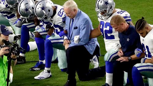 FILE - In this Monday, Sept. 25, 2017, file photo, the Dallas Cowboys, led by owner Jerry Jones, center, take a knee prior to the national anthem before an NFL football game against the Arizona Cardinals in Glendale, Ariz. What began more than a year ago with a lone NFL quarterback protesting police brutality against minorities by kneeling silently during the national anthem before games has grown into a roar with hundreds of players sitting, kneeling, locking arms or remaining in locker rooms, their reasons for demonstrating as varied as their methods. (AP Photo/Matt York, File)