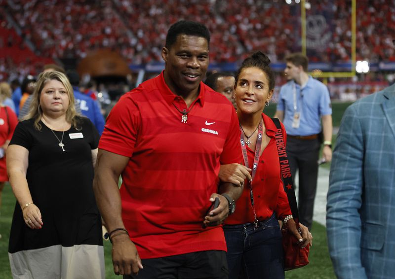 090322 Atlanta, Ga.: Former Georgia football player and Republican U.S. Senate candidate Herschel Walker walks with his wife, Julie, as they leave the field before Georgia’s game against the Oregon Ducks at Mercedes Benz Stadium, Saturday, September 3, 2022, in Atlanta. The Walker’s were on the field to honor former Georgia football coach Vince Dooley. (Jason Getz / Jason.Getz@ajc.com)