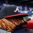 An Atlanta Braves hat and glove are shown near the steps of the dugout in between innings during their game against the Houston Astros at Truist Park, Friday, April 21, 2023, in Atlanta. The Braves lost to the Astros 6-4. Jason Getz / Jason.Getz@ajc.com)
