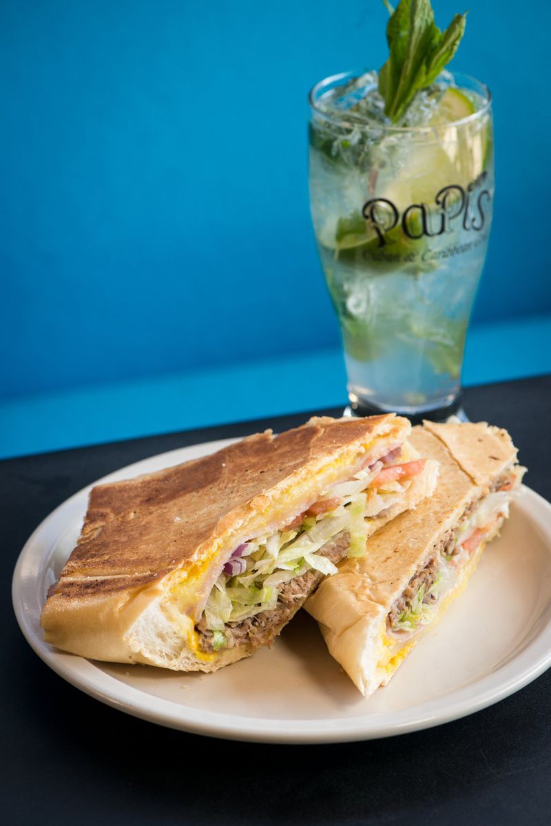 Rey’s Cuban sandwich with roast pork marinated with Papi’s secret recipe, ham, Swiss cheese, dill pickles, mustard and mayonnaise on Cuban bread, served here with a mojito. CONTRIBUTED BY MIA YAKEL