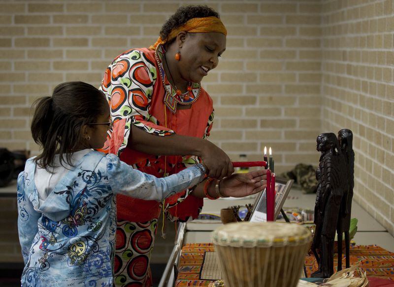 Elizabeth Kahura helps Lauryn Whitlock, 9, light a Kwanzaa candle at a Kwanzaa celebration at the Carver Museum. Jay Janner/AMERICAN-STATESMAN 2010