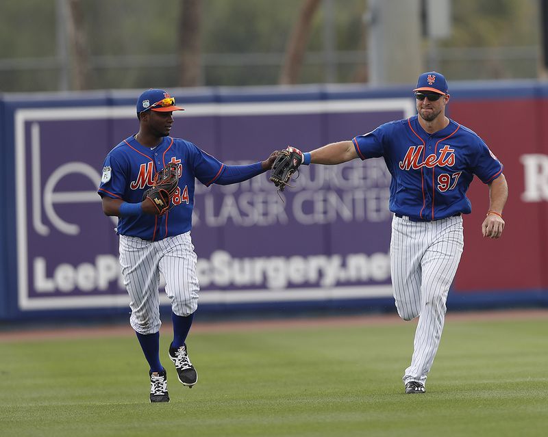 New York Mets right fielder Curtis Granderson (3) and left fielder Tim Tebow (97)  touch gloves as they run off the field following a Tebow catch against the Miami Marlins in a spring training baseball game Monday, March 13, 2017, in Port St. Lucie, Fla.