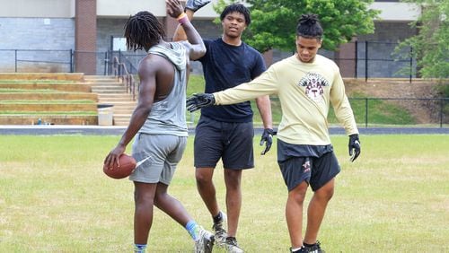 Camren Jackson (middle) and Kaece Supples (right) give high-fives to Keeman Hayes (left) in between one-on-ones during an unsanctioned player-led football practice on Thursday, June 4, 2020, at Tucker High School in Tucker, Georgia. The players planned the off-season practice despite uncertainty surrounding the upcoming football season amid coronavirus concerns. CHRISTINA MATACOTTA FOR THE ATLANTA JOURNAL-CONSTITUTION