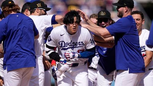 Los Angeles Dodgers' Shohei Ohtani, center, is congratulated by teammates after hitting a walk-off single during the 10th inning of a baseball game against the Cincinnati Reds Sunday, May 19, 2024, in Los Angeles. The Dodgers won 3-2. (AP Photo/Mark J. Terrill)