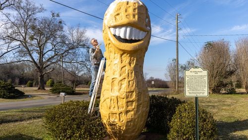 Plains resident Michael Dominick gives the Smiling Peanut a paint job Sunday in Plains. The statue was created in 1976 as part of Jimmy Carter's presidential campaign. (Arvin Temkar / arvin.temkar@ajc.com)