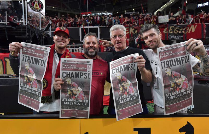 Atlanta United fans hold The Atlanta Journal-Constitution special edition after the team beat the Portland Timbers for the MLS championship  Saturday, Dec. 8, 2018, at Merceds-Benz Stadium. 