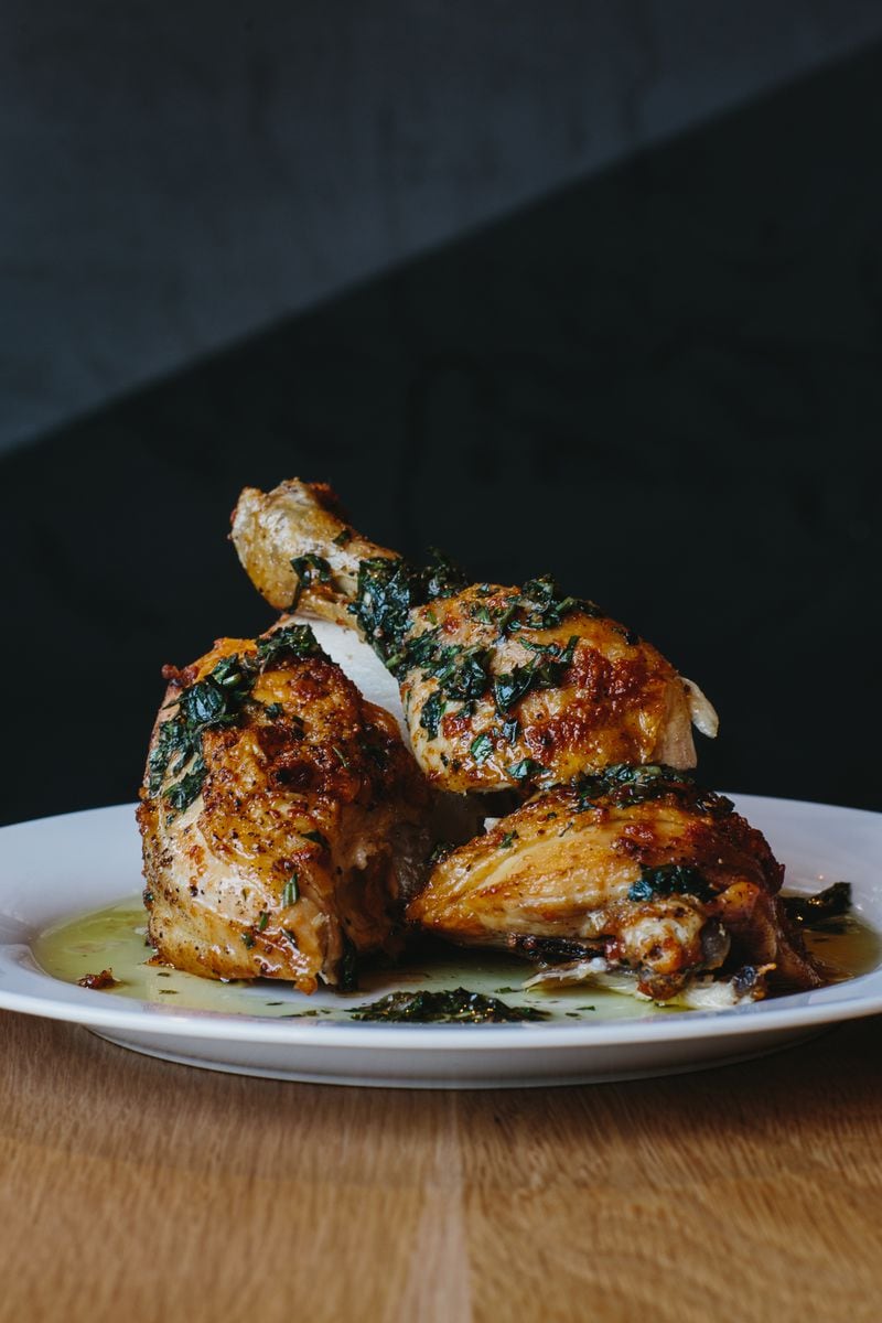 Simple roast chicken is served in a pool of olive oil and herbs at Brezza Cucina. Credit: Andrew Thomas Lee