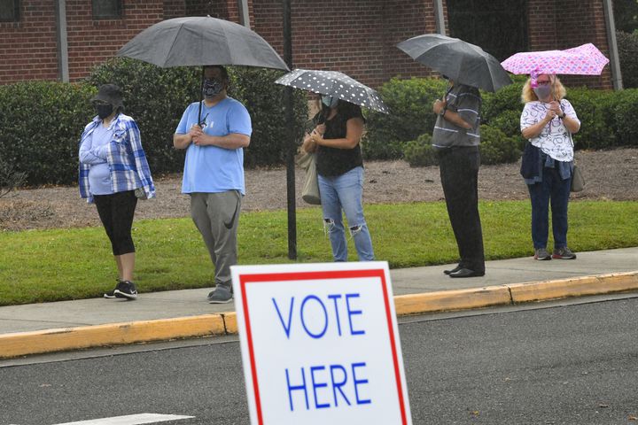 Voters brave the rain and a three hour wait line as the first day of early voting is shown underway on Monday, Oct. 12, 2020, at George Pierce Park in Suwanee, Ga. JOHN AMIS FOR THE ATLANTA JOURNAL- CONSTITUTION