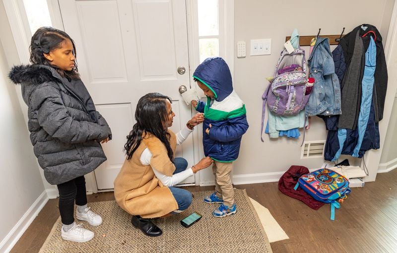 Kristal Seymour (center) helps 6-year-old Brian Seymour III with his jacket while Kayden Seymour(left), a fourth grader, waits to leave the house. Kristal Seymour says she finds critical race theory "nonexistent" in her children's educations. (Jenni Girtman for The Atlanta Journal-Constitution)