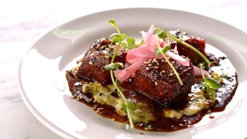 An order of Peppered Pork Belly at City Pharmacy brings fatty, salty chunks glistening with a sorghum glaze over a pool of creamed leeks. Photo courtesy City Pharmacy