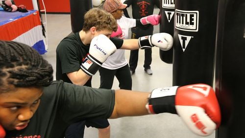 Members of Congress are contemplating whether to allow taxpayers to write-off spending for fitness activities. Some think that could be good for the sweat business. Danielle Huggins (from left), Carter Coffie, and Marty Lewis punch bags while Marty Hill teaches their boxing fitness class at Sweet Science Fitness Boxing Club in Doraville. Curtis Compton/ccompton@ajc.com