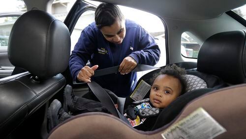 In this Friday, May 15, 2015 photo, Shannon Henderson buckles her son, Justin, 1, into his car seat for the ride to his father's house before she goes to her job as a part-time customer service representative at Wal-Mart in Sacramento, Calif. (AP Photo/Rich Pedroncelli)
