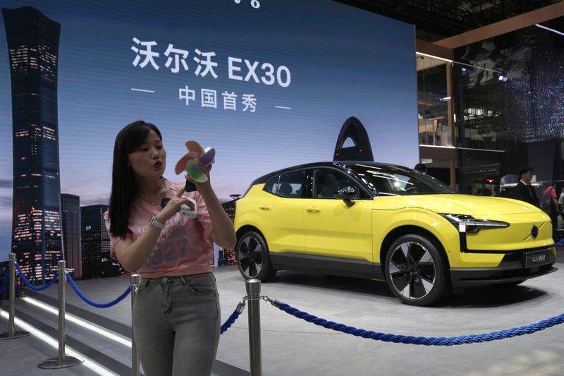 A live streamer works near the Volvo EX30 fully electric small SUV unveiled during Auto China 2024 in Beijing, Thursday, April 25, 2024. Global automakers and EV startups unveiled new models and concept cars at China's largest auto show on Thursday, with a focus on the nation's transformation into a major market and production base for digitally connected, new-energy vehicles. (AP Photo/Ng Han Guan)